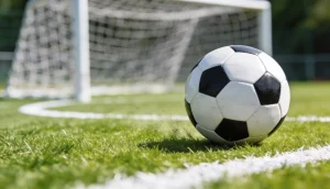 Fodbold der ruller mod mål pa groent graes med hvide striber pa en udendoers fodboldbane
