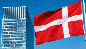 Dansk flag der vejer foran en kontorbygning i København pa en klar dag